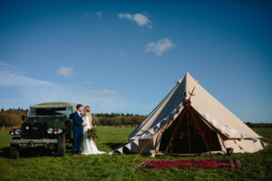 Bride and Groom outside a bell tent standing next to a Land Rover