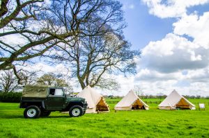 Land rover parked out side three Bell Tents